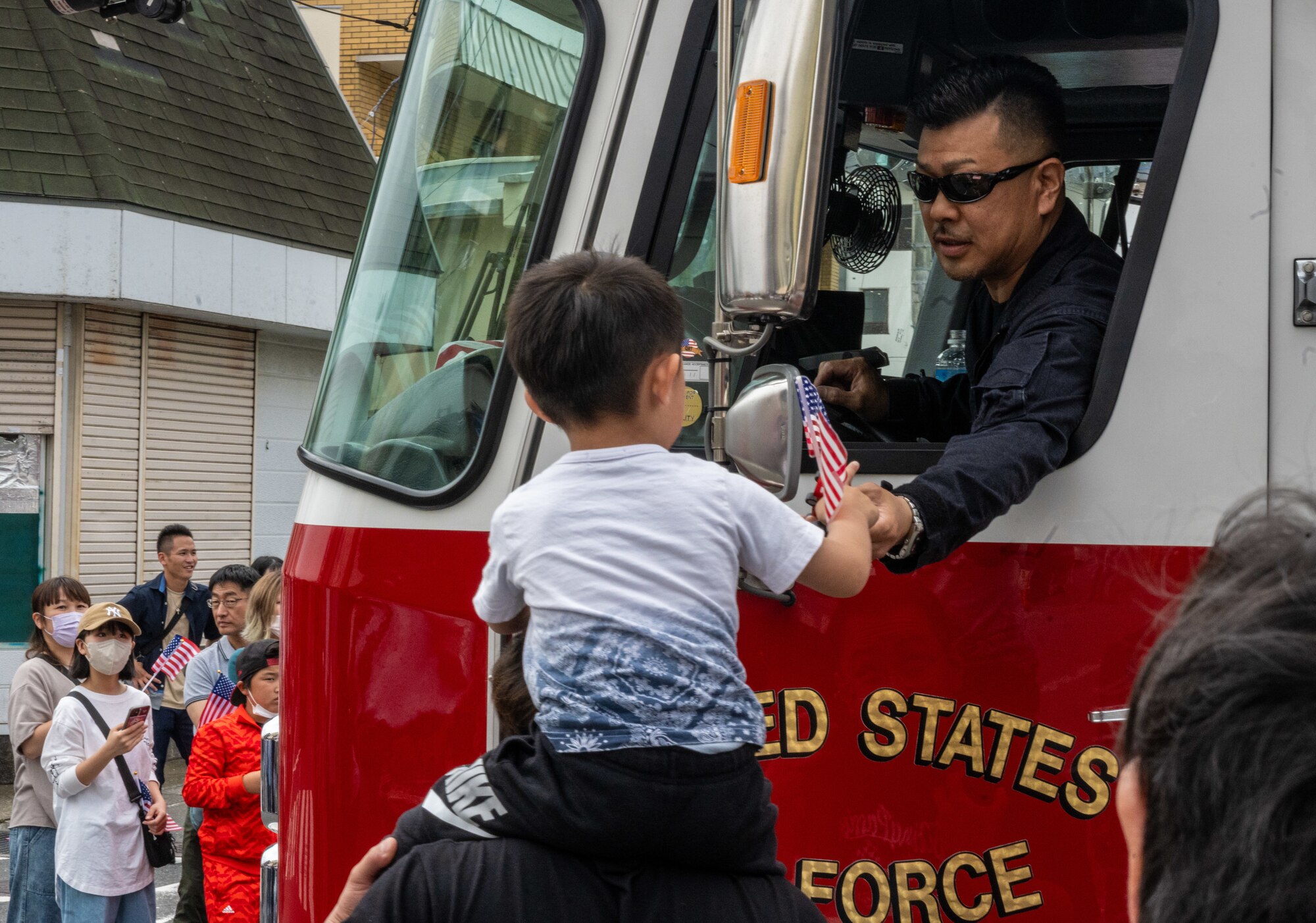 A Japanese kid receives a toy from a firefighter during the American Day parade in Misawa City, Japan, June 25, 2023. Events like these are important as they afford Misawa’s local community, American and Japanese alike, opportunities to interact in a relaxed environment meant to build friendships and strengthen partnerships. (U.S. Air Force photo by Staff Sgt. Kristen Heller)