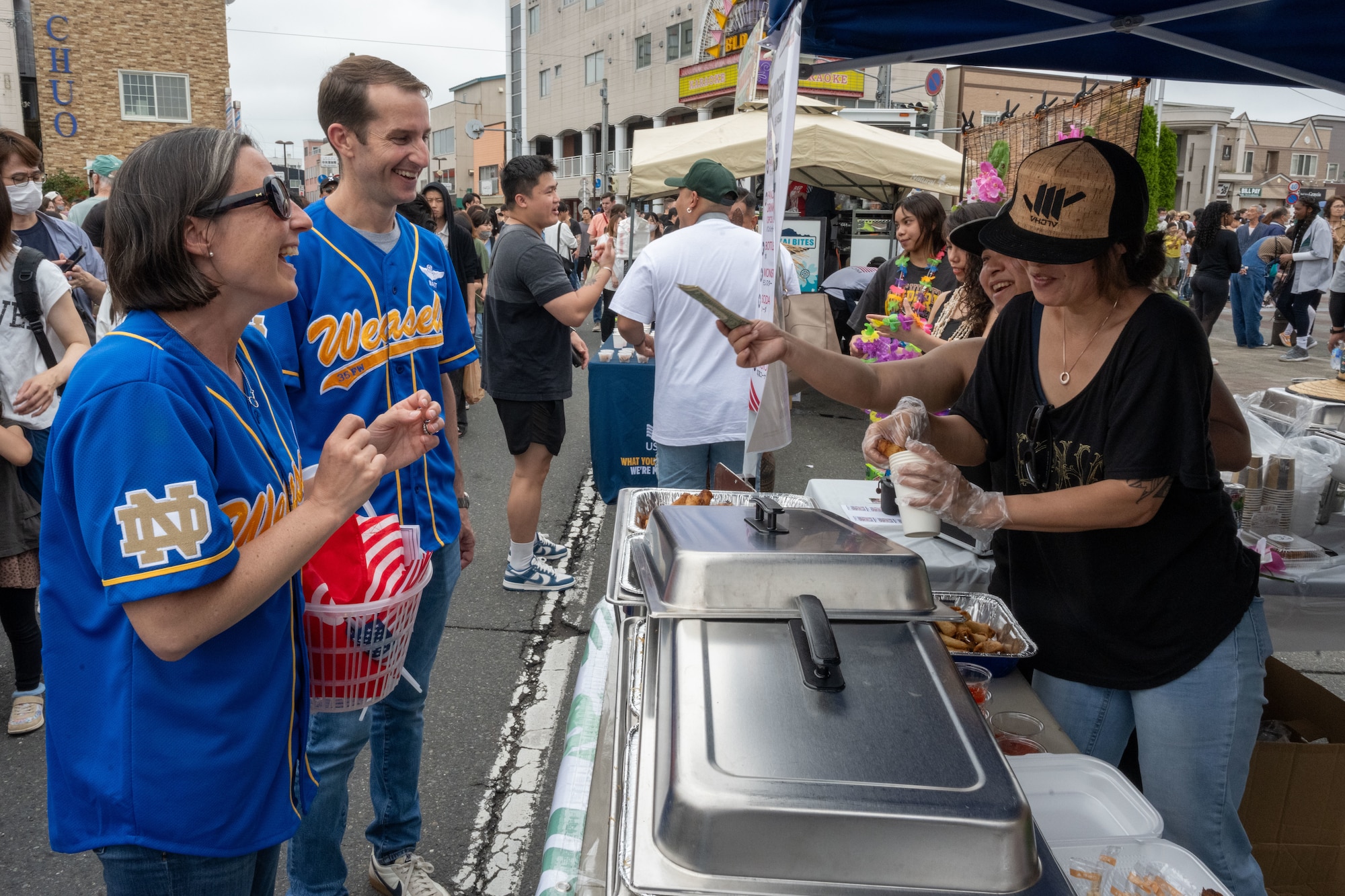 U.S. Air Force Col. Michael Richard, 35th Fighter Wing commander, and his spouse Jessica Richard purchase food from a local vendor during American Day in Misawa City, Japan, June 25, 2023. American Day is one of the largest cross-cultural festivals in the area and it made a return after being on hiatus due to COVID-19. The event, drawing over 50,000 visitors, took on the theme “two cultures, but one community.” (U.S. Air Force photo by Staff Sgt. Kristen Heller)