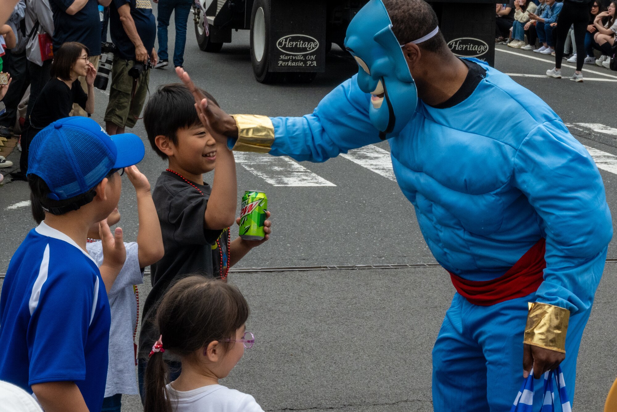 An American dressed in cosplay for the American Day parade high fives Japanese kids in Misawa City, Japan, June 25, 2023. American Day is one of the largest cross-cultural festivals in the area and it made a return after being on hiatus due to COVID-19. The event, drawing over 50,000 visitors, took on the theme “two cultures, but one community.” (U.S. Air Force photo by Staff Sgt. Kristen Heller)