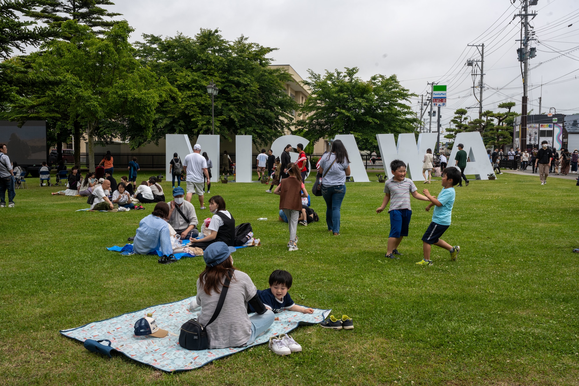 Japanese and American attendees of American Day gather in front of the Misawa City sign outside of Friendship Gate to play and relax during the festivities in Misawa City, Japan, June 25, 2023. American Day is one of the largest cross-cultural festivals in the area and it made a return after being on hiatus due to COVID-19. The event, drawing over 50,000 visitors, took on the theme “two cultures, but one community.” (U.S. Air Force photo by Staff Sgt. Kristen Heller)