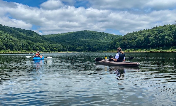 Two boaters kayak across a reservoir