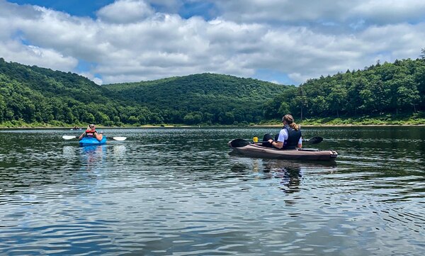 Two boaters kayak across a reservoir