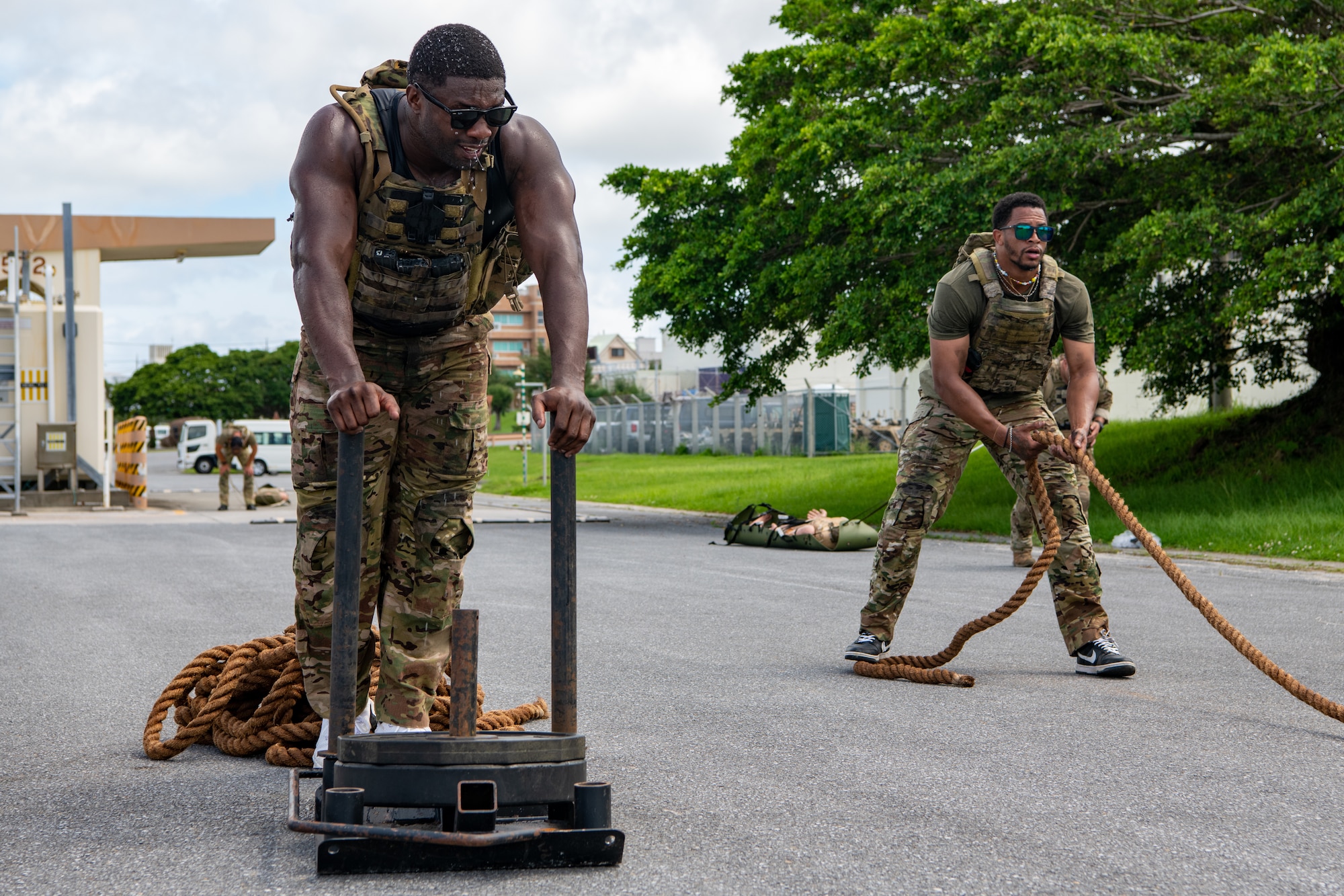 A man on the left pushes weights; A man on the right, pulls a rope.