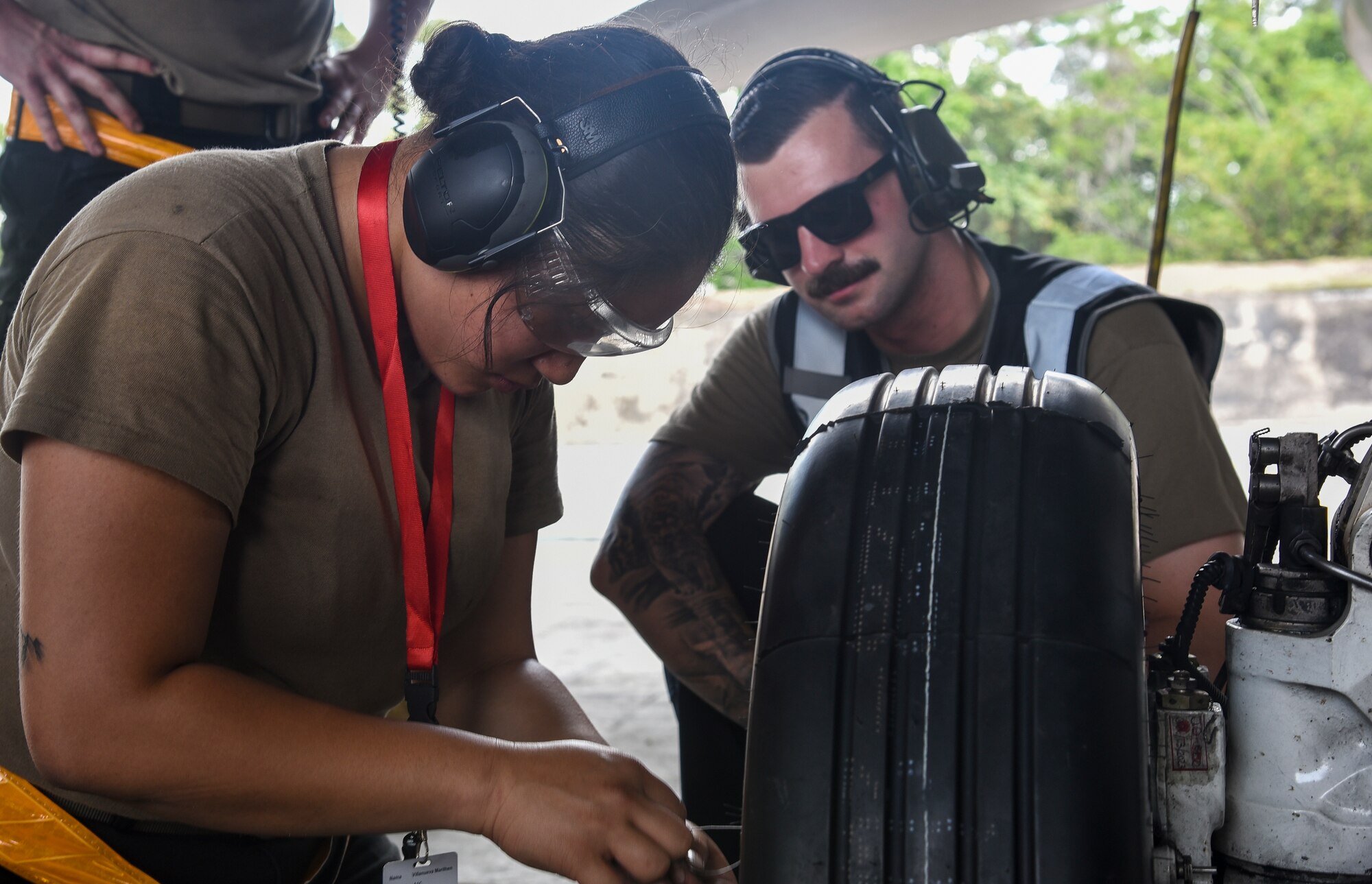 A crew chief observes an Ariman working on a wheel