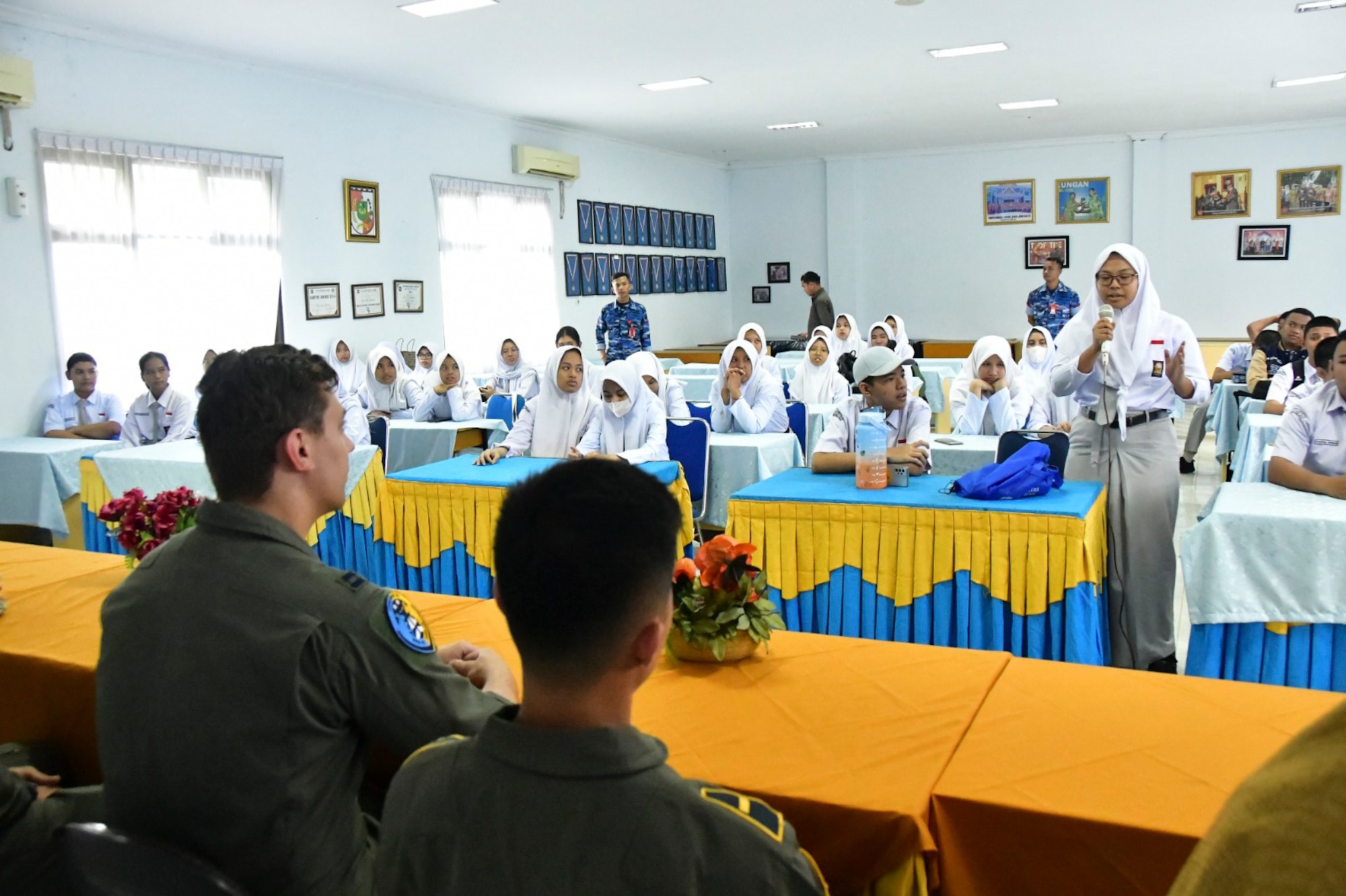 A large classroom of students ask questions to a panel of pilots and maintainers