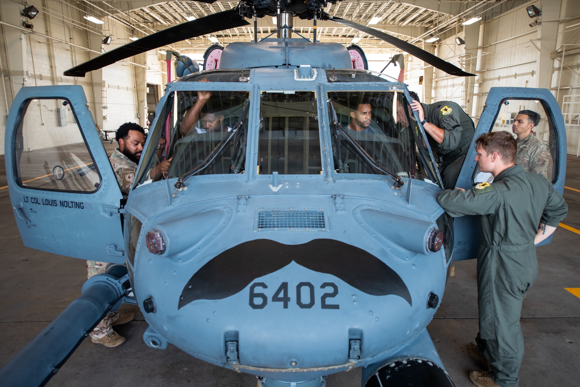Several man crowed around the cockpit of a helicopter.