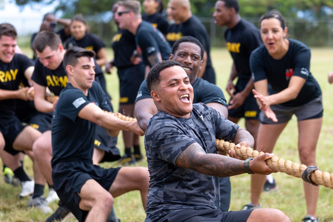 Soldiers pull on a thick rope while being cheered on by other soldiers.