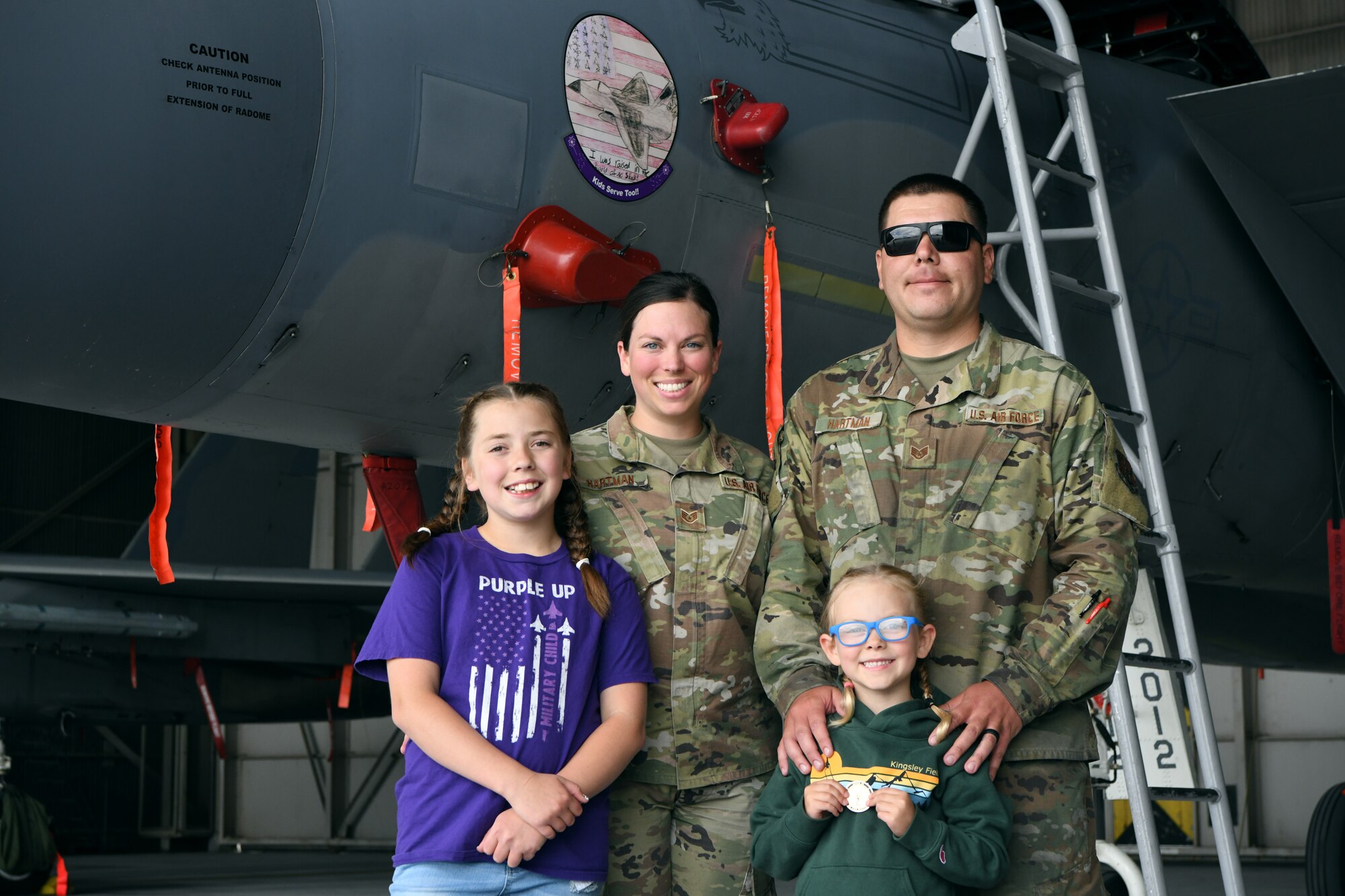 U.S. Air Force Staff Sgts. Michael and Ashyln Hartman, 173rd Maintenance Group, pose for a photo with their daughters June 23, 2023. Eleven-year-old Kaeylnn, left, designed the artwork on the nose of an F-15C at Kingsley Field in Klamath Falls Falls, Oregon, in a Month of the Military Child contest.