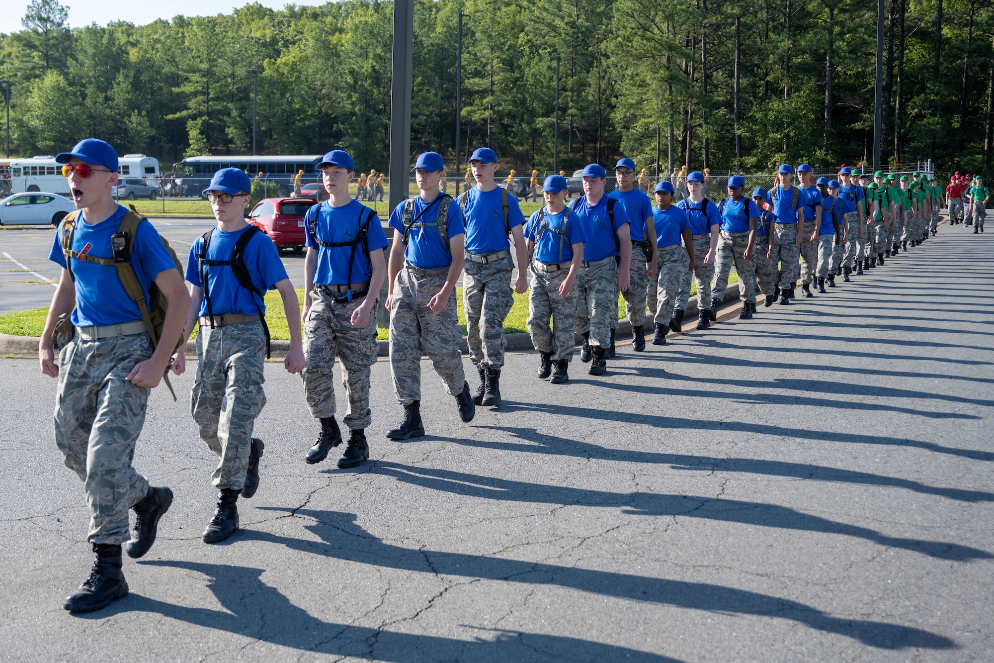 Civil Air Patrol Cadets wearing blue and green shirts walk in a line on the road