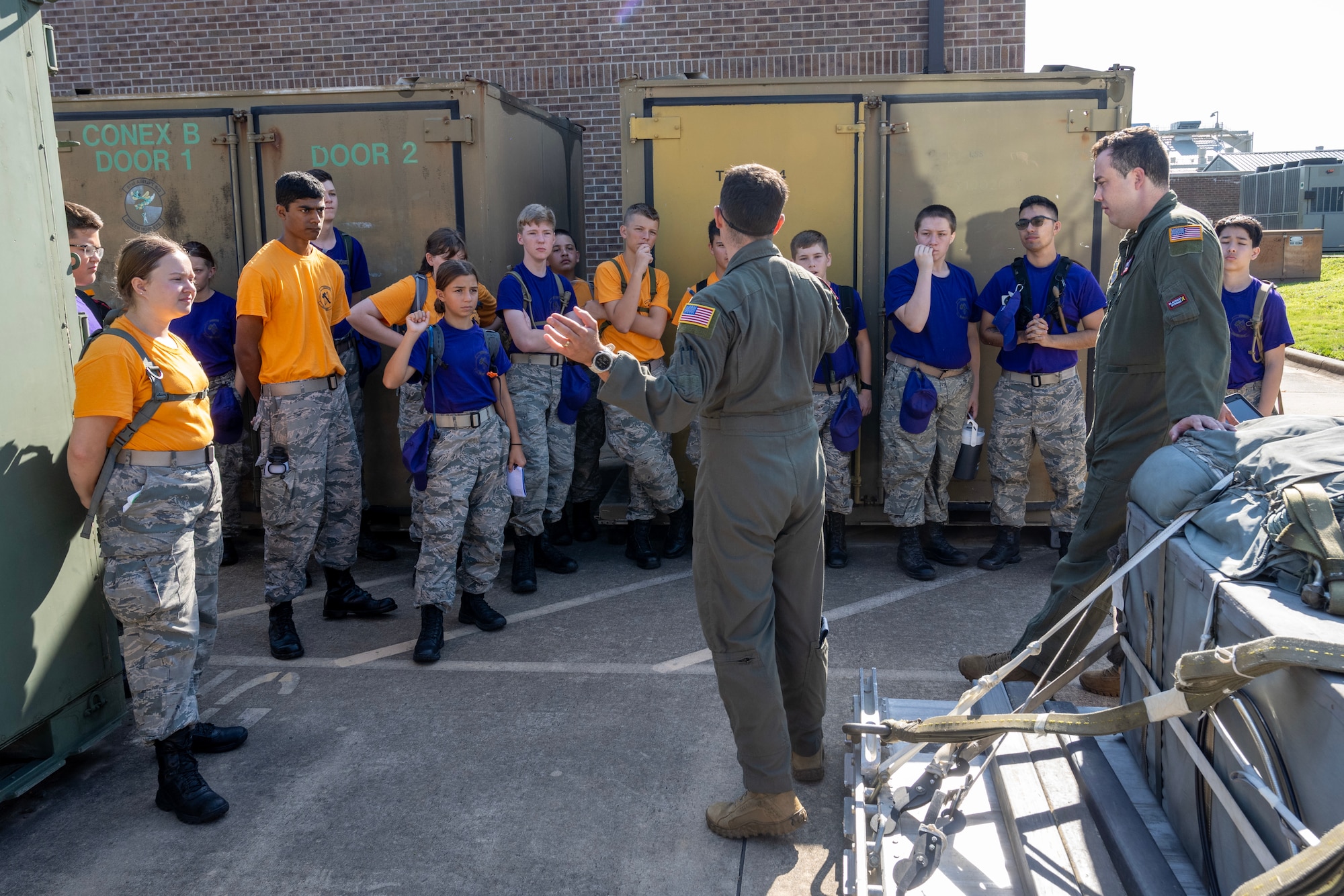 Two male Airmen speak to Civil Air Patrol cadets wearing purple and yellow shirts
