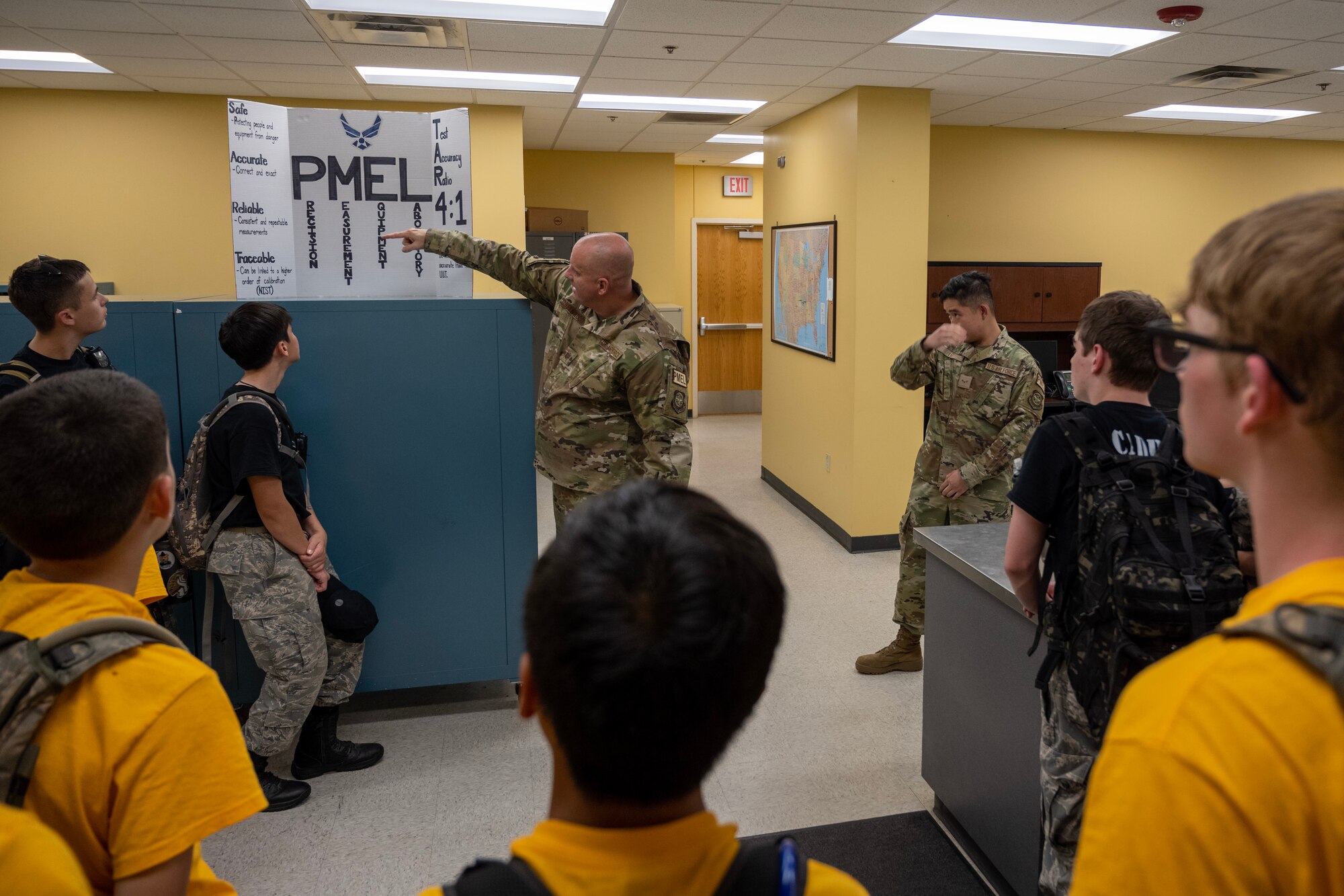 A male Airman uses a tri-fold poster to explain his office mission to Civil Air Patrol Cadets