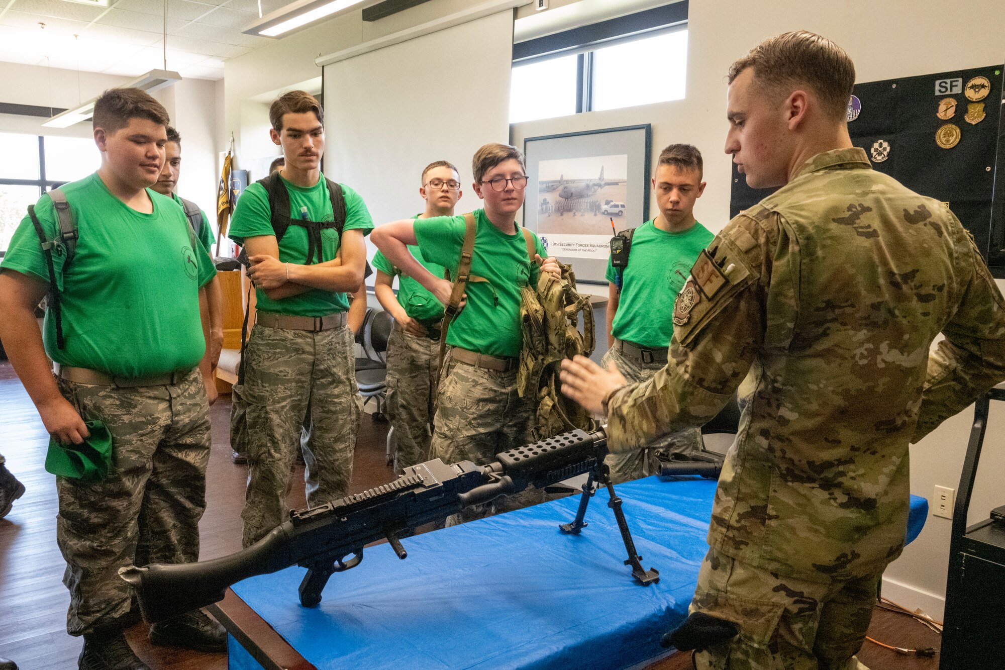 A male Airman speaks to Civil Air Patrol cadets with various weapons systems on a table
