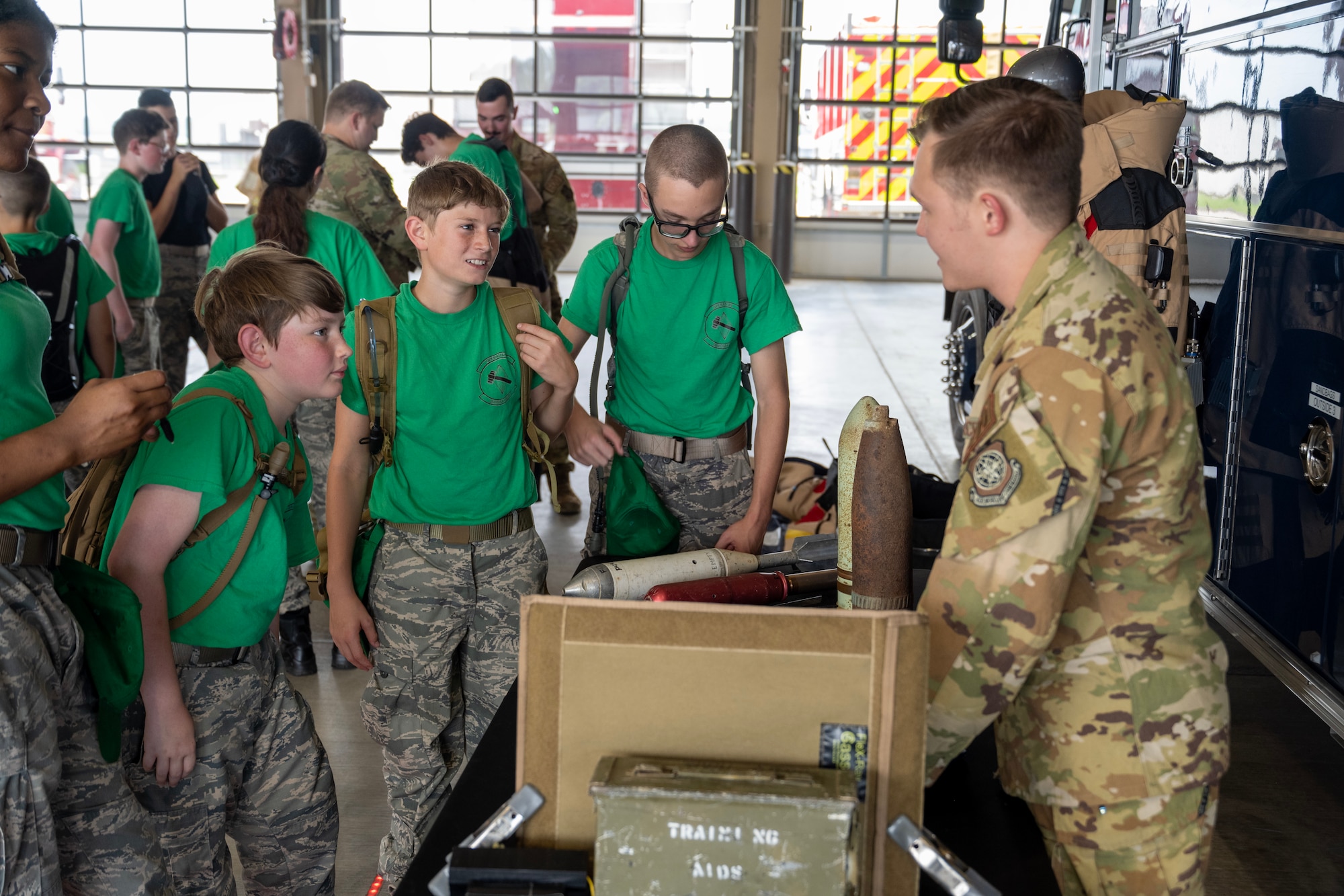 A male Airman speaks to Civil Air Patrol cadets with props on a table