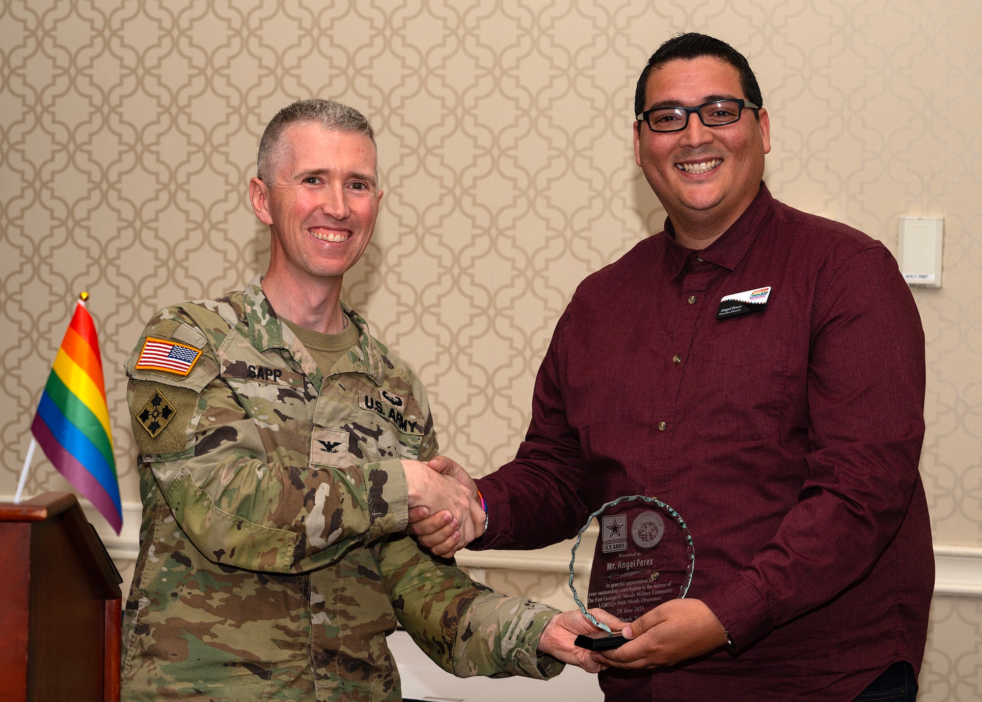 U.S. Army Col. Michael A. Sapp, Fort George G. Meade Garrison commander, presents an appreciation award to Angel Perez, Caroline Pride chief executive officer and executive director, during a Pride Month symposium, June 28, 2023, at Fort George G. Meade, Maryland. Fort Meade Garrison and 70th Intelligence Surveillance, Reconnaissance Wing Diversity & Inclusion council hosted the event to celebrate, recognize and educate communities to uphold equality, dignity, and respect for all. (U.S. Air Force photo by Staff Sgt. Kevin Iinuma)