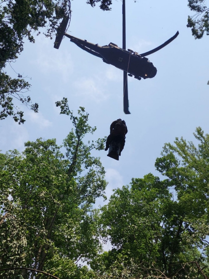 Sgt. 1st Class Giovanni DeZuani, a fight paramedic with the Tennessee Army National Guard, is hoisted into a hovering Black Hawk helicopter with an injured hiker immobilized on a stretcher during a rescue at the Cumberland Gap National Historic Park June 28, 2023.