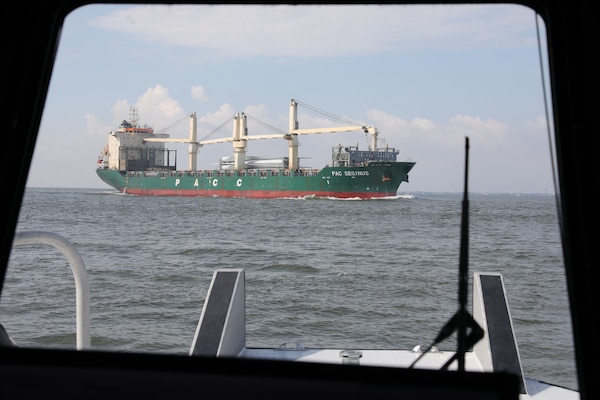 The cargo container marine vessel PAC Seginus steams north with a cargo of wind turbine blades in the Houston Shipping Channel as the crew of the USACE Galveston District survey boat Tanner II waits for the ship to pass.