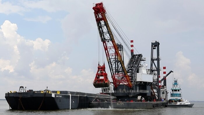 The DB Avalon, one of the largest clamshell dredges in North America, drops a 30 cubic yard load of dredge material onto the Sand Point barge, in the Houston Shipping Channel.