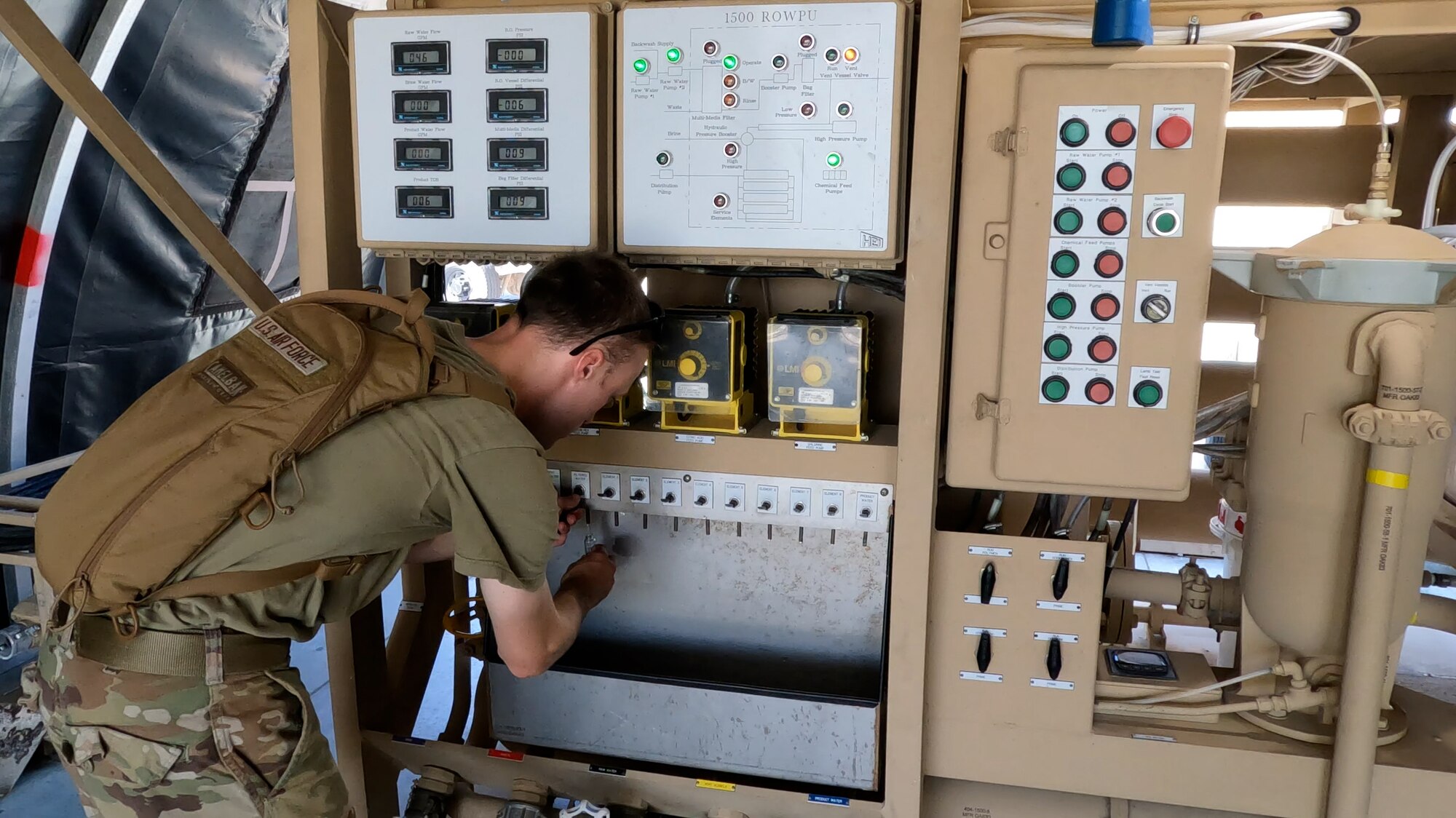 airman draws water from a small valve on the ROWPU in a field conditions environment