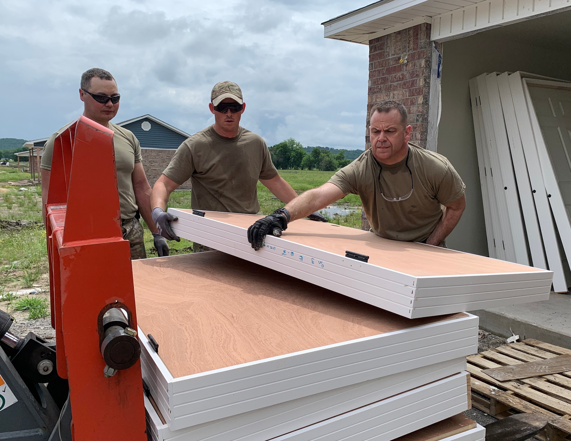 U.S. Air Force Master Sgt. Justin Laney, Master Sgt. Matthew Woodham and Tech. Sgt. Ed Raati, 133rd Civil Engineer Squadron, offload doors in Tahlequah, Olka., May 15, 2023.