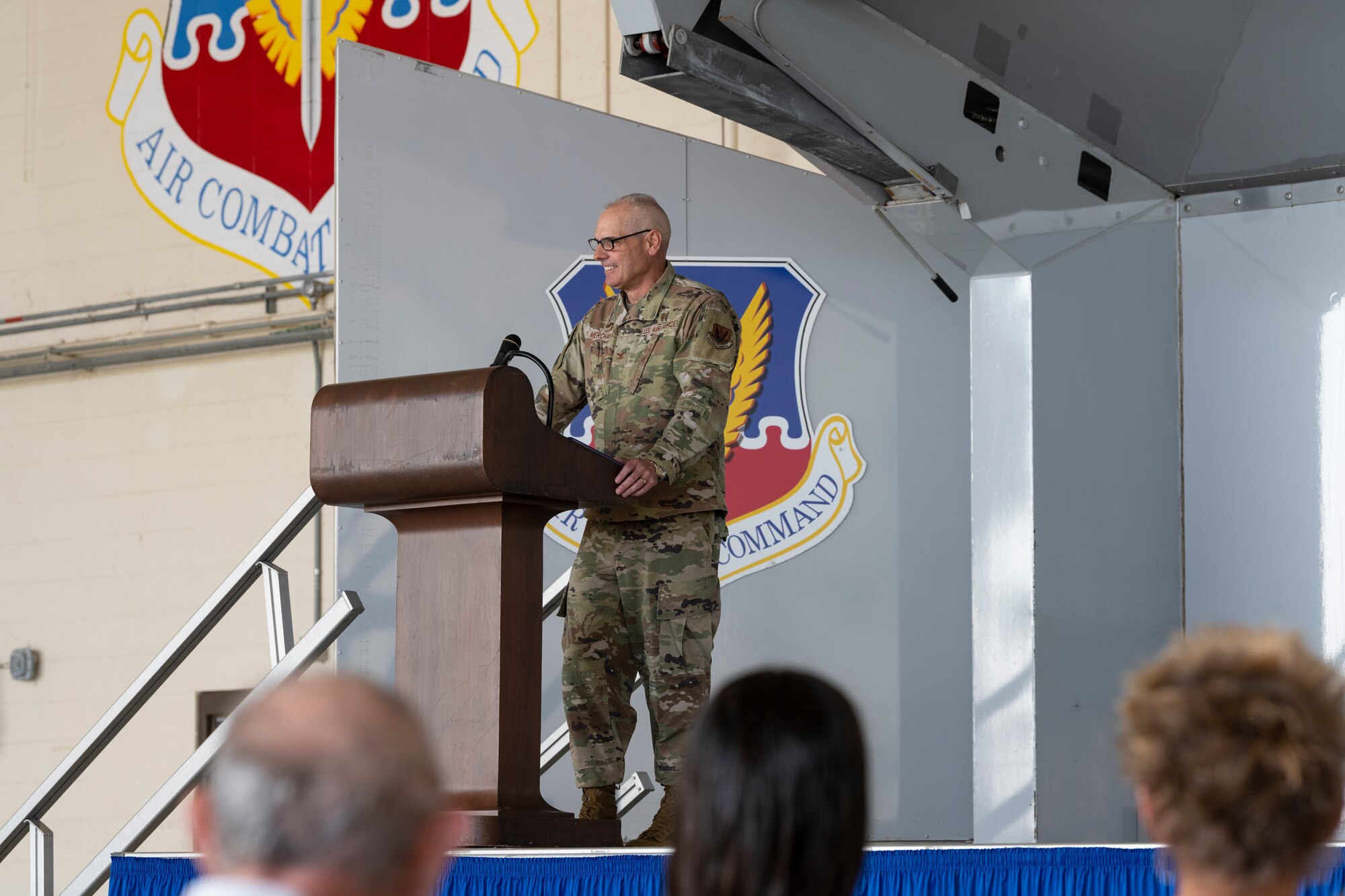 A photo of a man in a U.S. military uniform standing behind a podium on stage.