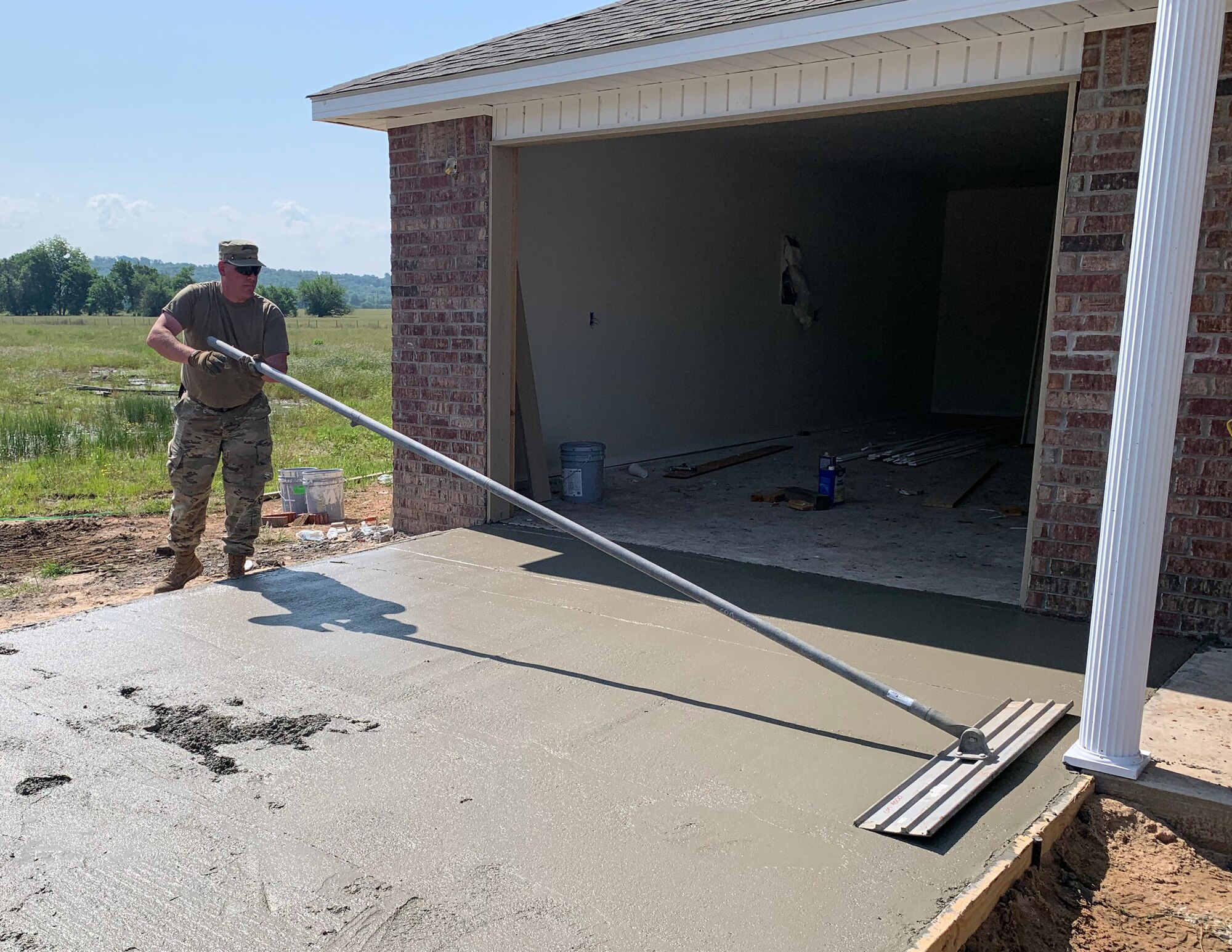 U.S. Air Force Staff Sgt. Brian Leesch, 133rd Civil Engineer Squadron, finishes a newly poured concrete driveway apron in Tahlequah, Olka., May 22, 2023.