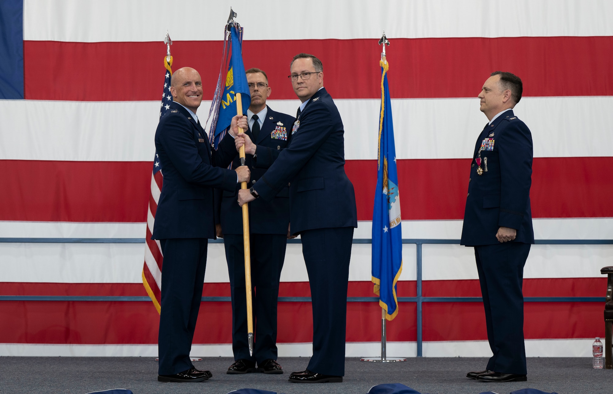 U.S. Air Force Col. Derek Oakley, 28th Bomb Wing commander, left, presents the 28th Maintenance Group guidon to Col. Johnny West, incoming 28th MXG commander during a change of command ceremony at Ellsworth Air Force Base, South Dakota, June 29, 2023.