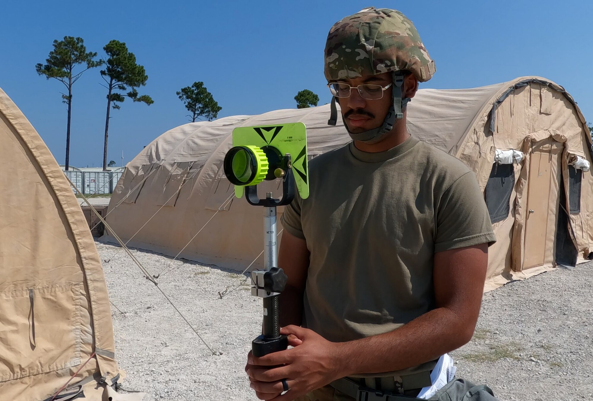 Airman holds surveying equipment so teammate can take a reading