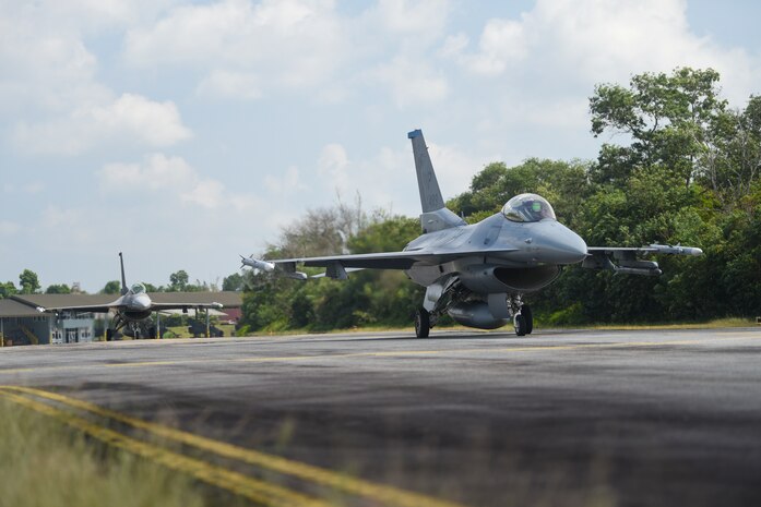 Two planes taxi against a jungle backdrop