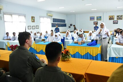 A large classroom of students ask questions to a panel of pilots and maintainers