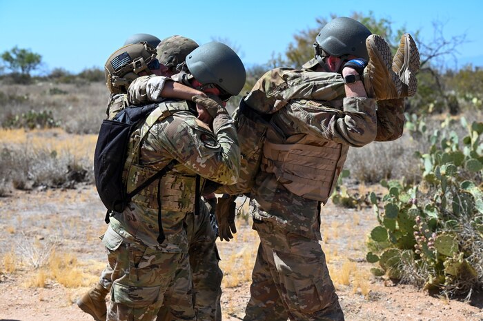 A photo of three men in military uniforms carrying a fourth man in uniform.