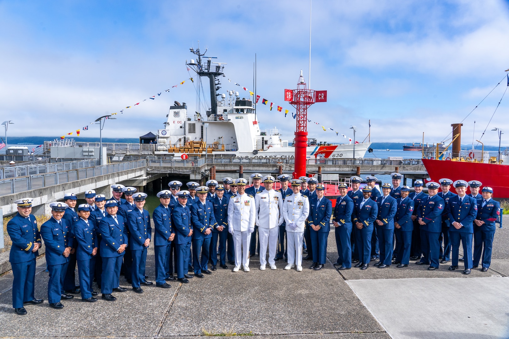Cmdr. Lee Crusius, the commanding officer of Coast Guard Cutter Alert (WMEC 630), Lt. Cmdr. Nicholas Sharpe, the executive officer, and Cmdr. Matthew Kolodica pose for a photo with the cutter's crew in Astoria, Oregon, June 29, 2023. The crew conducted a change of command ceremony, where Crusius relieved Kolodica as the Alert's commanding officer. (U.S. Coast Guard photo by Petty Officer 1st Class Travis Magee)