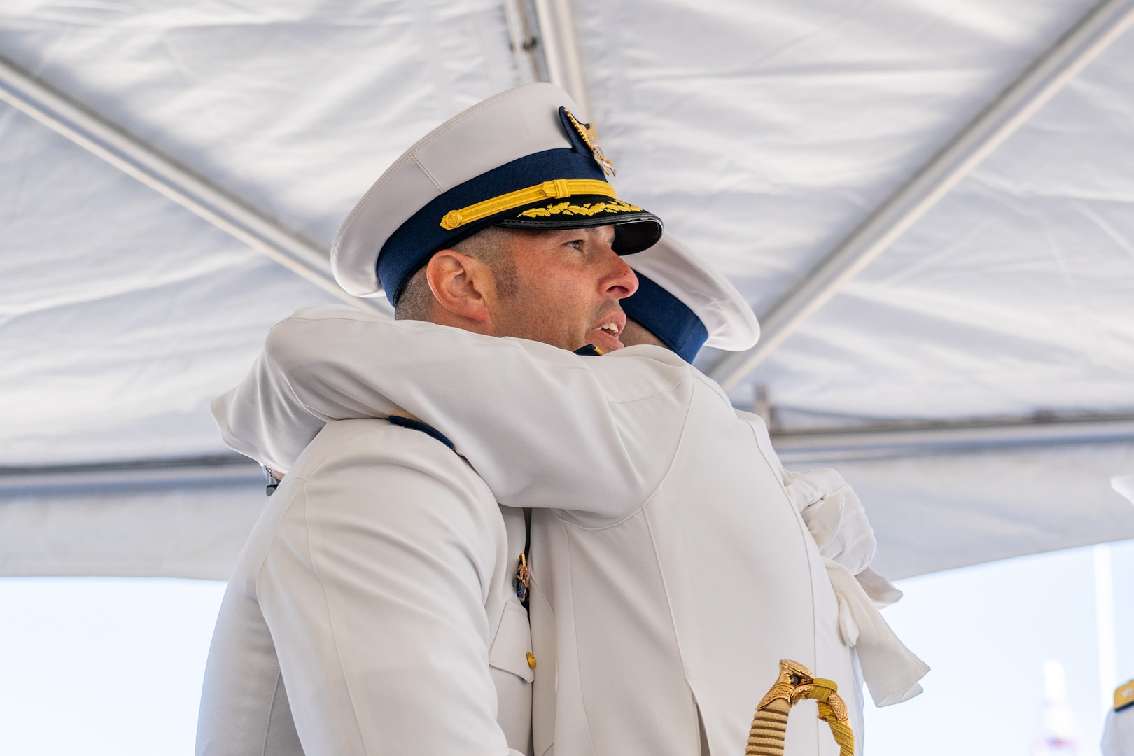 Cmdr. Lee Crusius, the commanding officer of Coast Guard Cutter Alert (WMEC 630), hugs Cmdr. Matthew Kolodica during a change of command ceremony in Astoria, Oregon, June 29, 2023. During the ceremony, Crusius relieved Kolodica as the cutter’s commanding officer. (U.S. Coast Guard photo by Petty Officer 1st Class Travis Magee)