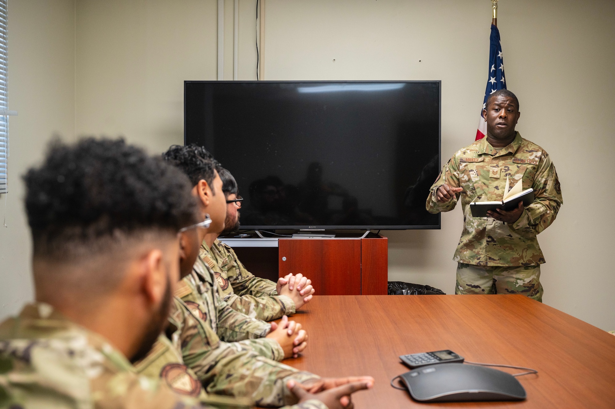 Airman briefs other Airmen during a meeting.