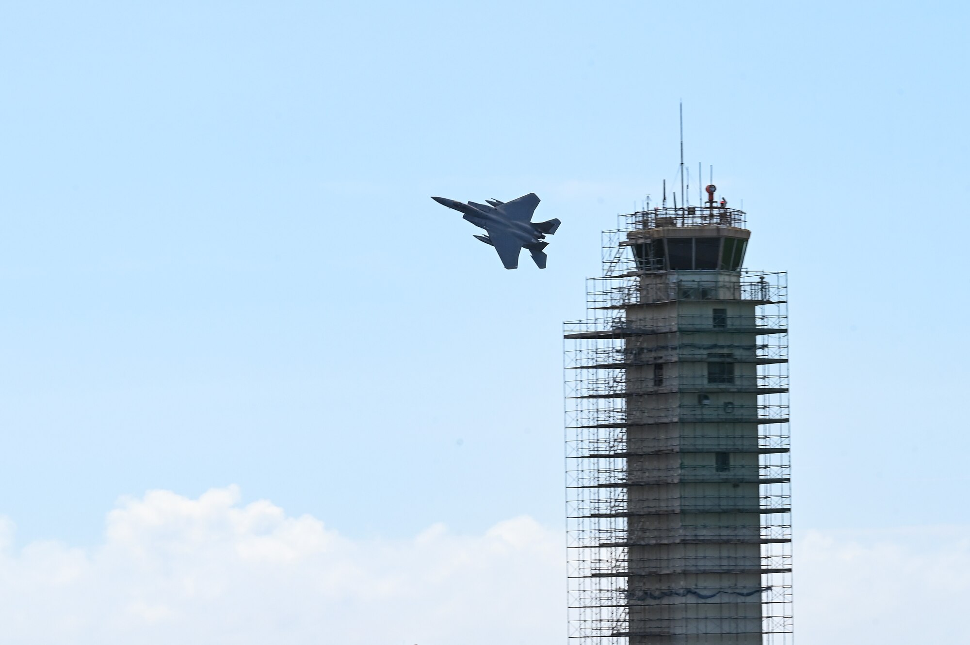 An aircraft flies behind the air traffic control tower.