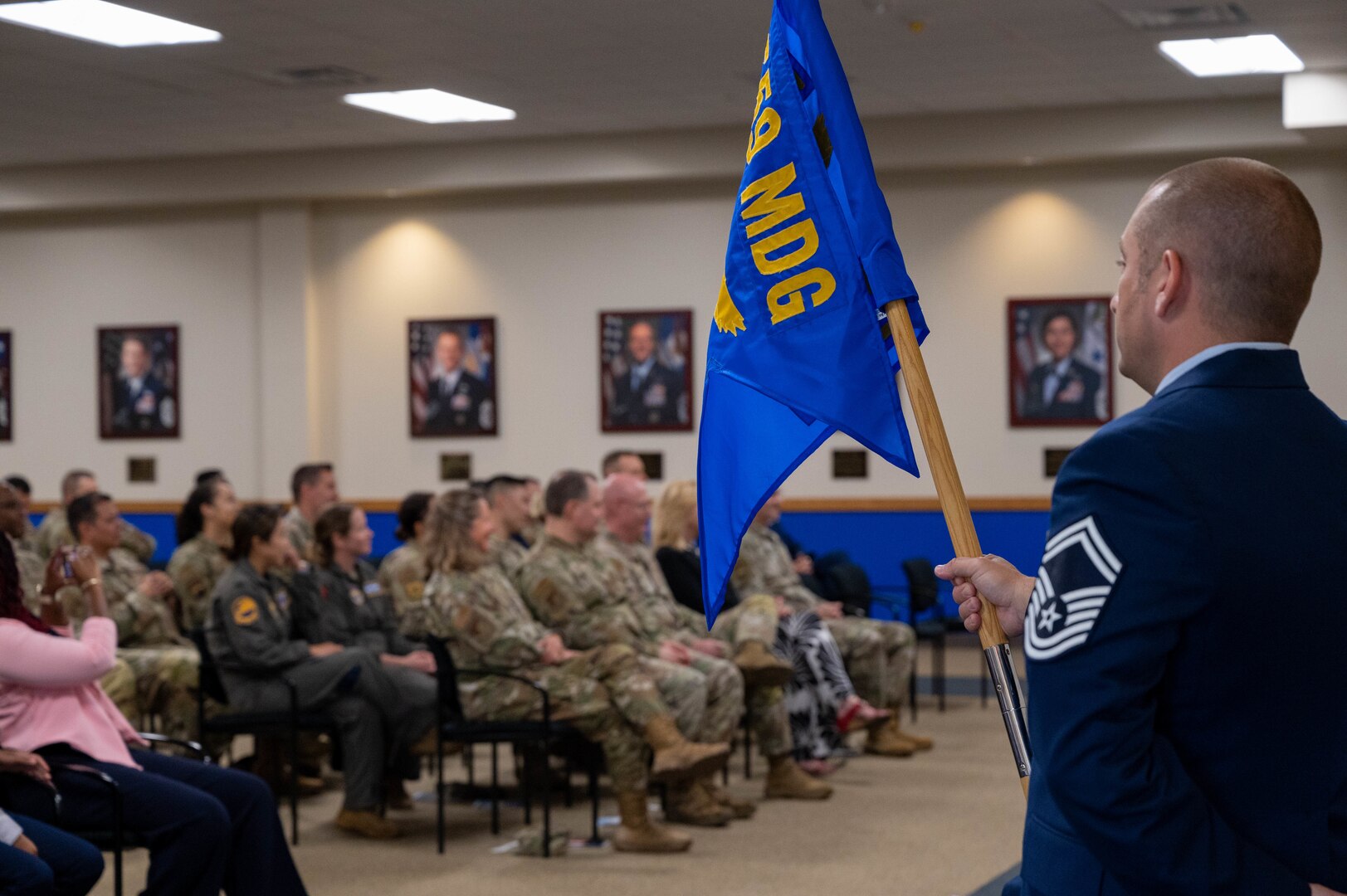 Senior Master Sgt. Jonathan Eckley, 559th Trainee Health Squadron senior enlisted leader, holds the guidon as Lt. Col. Lena Williams Cox, newly appointed commander of the 559th THLS addresses attendees during the change of command ceremony at Joint Base San Antonio- Lackland, Texas.