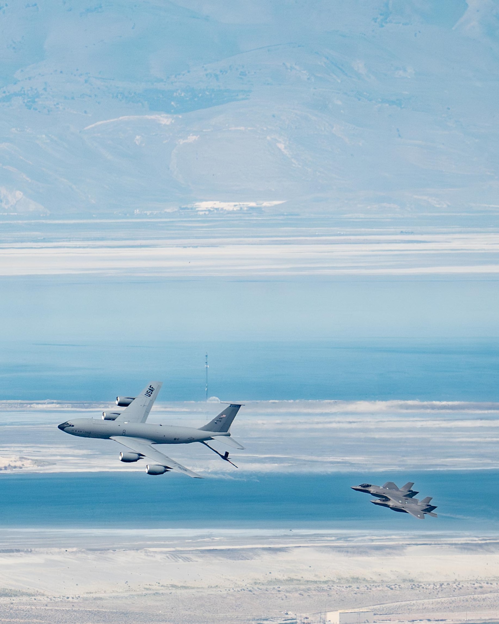 An F-35 fighter aircraft flies with a KC-135 refueler