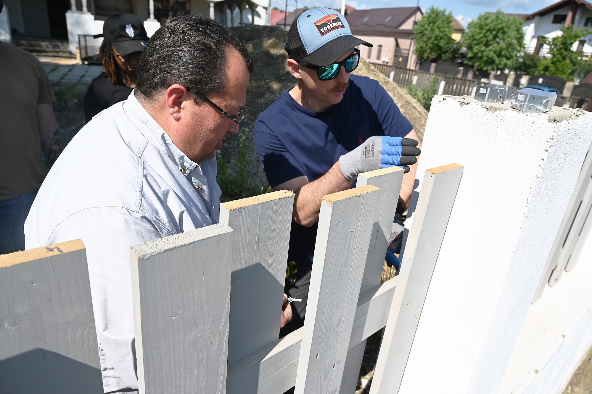 Men install a white fence