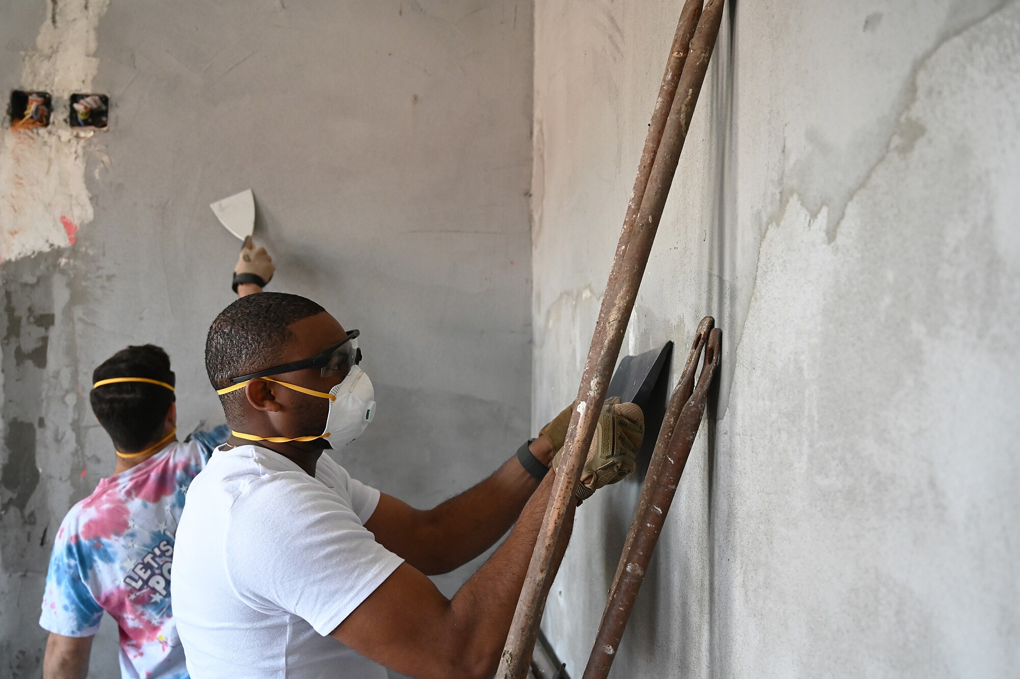 man sands a wall