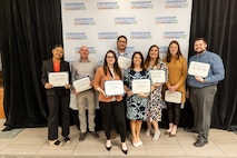 Group of people pose for photo with their awards.