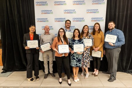 Group of people pose for photo with their awards.