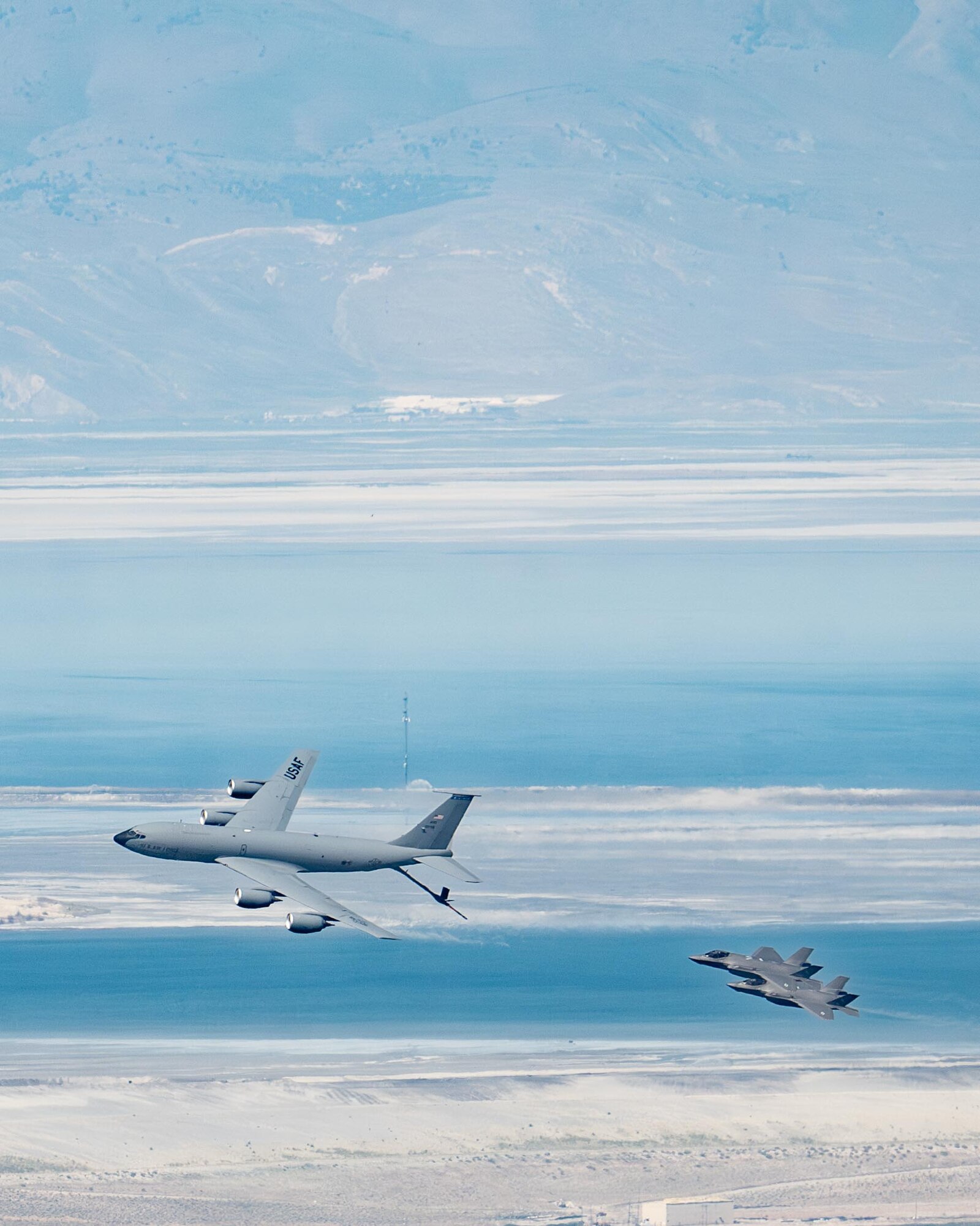 An F-35 fighter aircraft flies with a KC-135 refueler