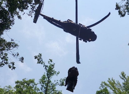 Sgt. 1st Class Giovanni DeZuani, a fight paramedic with the Tennessee Army National Guard, is hoisted into a hovering Black Hawk helicopter with an injured hiker immobilized on a stretcher during a rescue at the Cumberland Gap National Historic Park June 28, 2023.