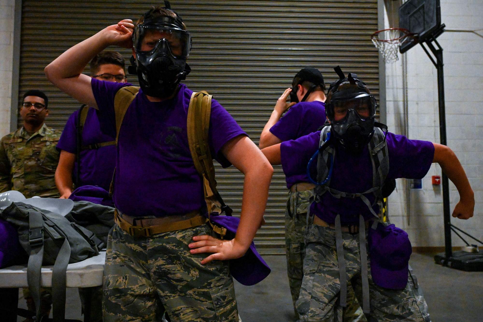 Civil Air Patrol Cadets wearing purple shirts try on gas masks.