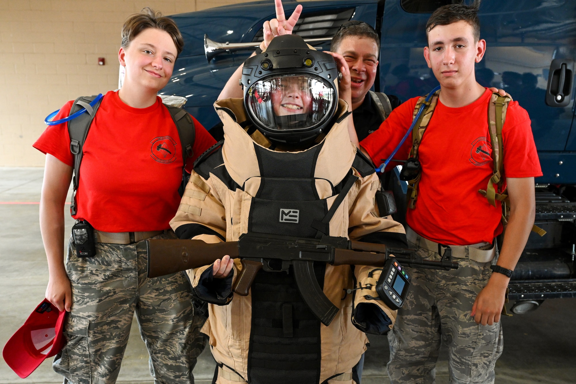 A Civil Air Patrol Cadet poses for a photo in an EOD bomb with his fellow cadets in red shirts.