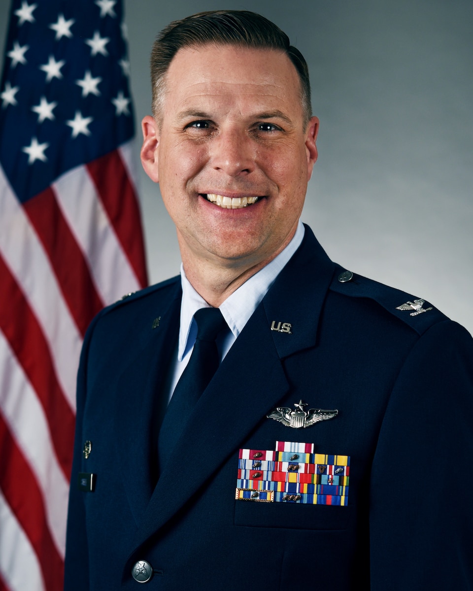 A man in a blue uniform smiles at the camera.