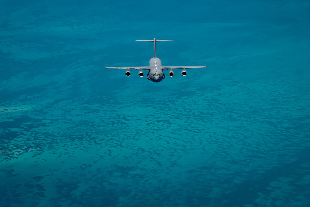 An Air Force aircraft flies over open water.