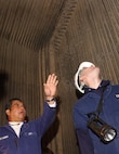 Cris Cueto, supervisor and marine inspector of the barge section at U. S. Coast Guard Activities New York, explains to Lieutenant John Miller how to inspect the inside of a propulsion boiler onboard a steam-powered passenger vessel in the New York Harbor Nov. 25, 2002.