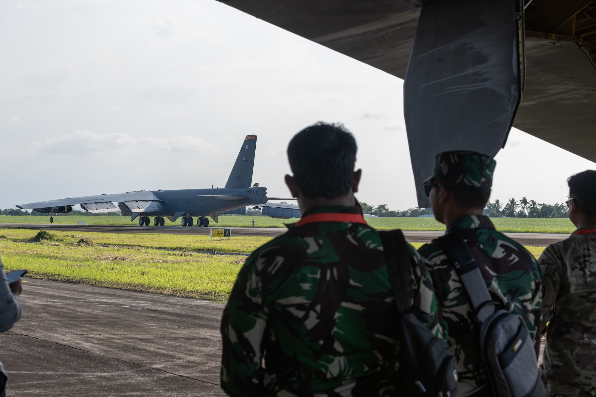 Members of the Tentara Nasional Indonesia Angkatan Udara, or Indonesian Air Force, seek shade under the wing of a U.S. Air Force B-52H Stratofortress assigned to the 23rd Bomb Squadron at Minot Air Force Base, North Dakota, while a second 23rd BS B-52 taxis on the runway upon landing at the Kualanamu International Airport in Medan, Indonesia, June 19, 2023. The arrival of the B-52s marked the first time U.S. Air Force B-52s had landed on Indonesian soil. (U.S. Air Force photo by Tech. Sgt. Zade Vadnais)
