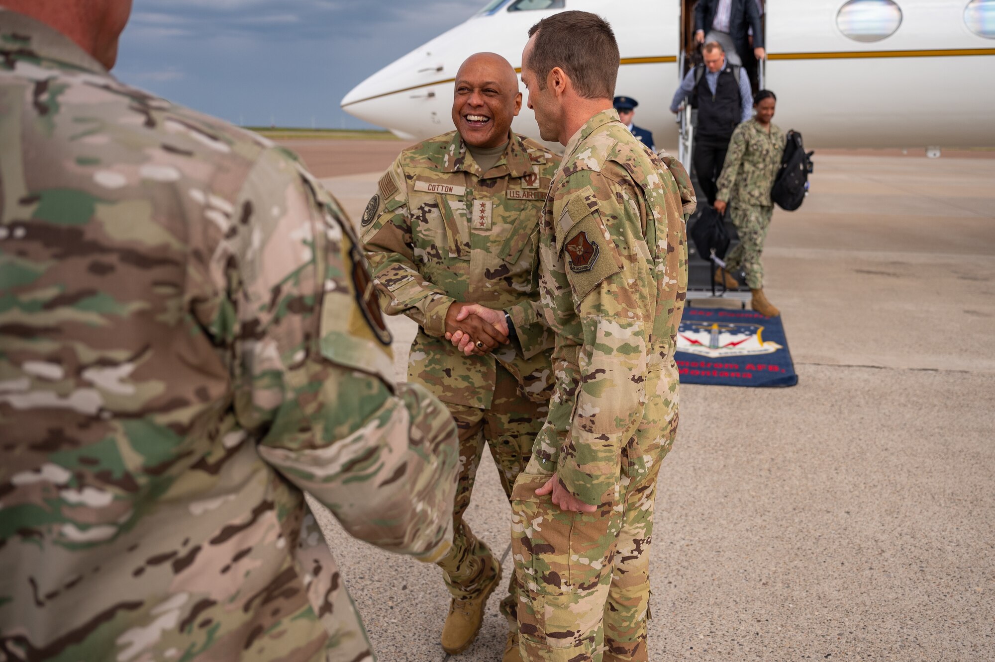 Two men in military uniform greet each other via handshake.
