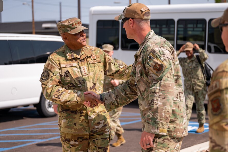 Two men in military uniform greet each other via handshake.
